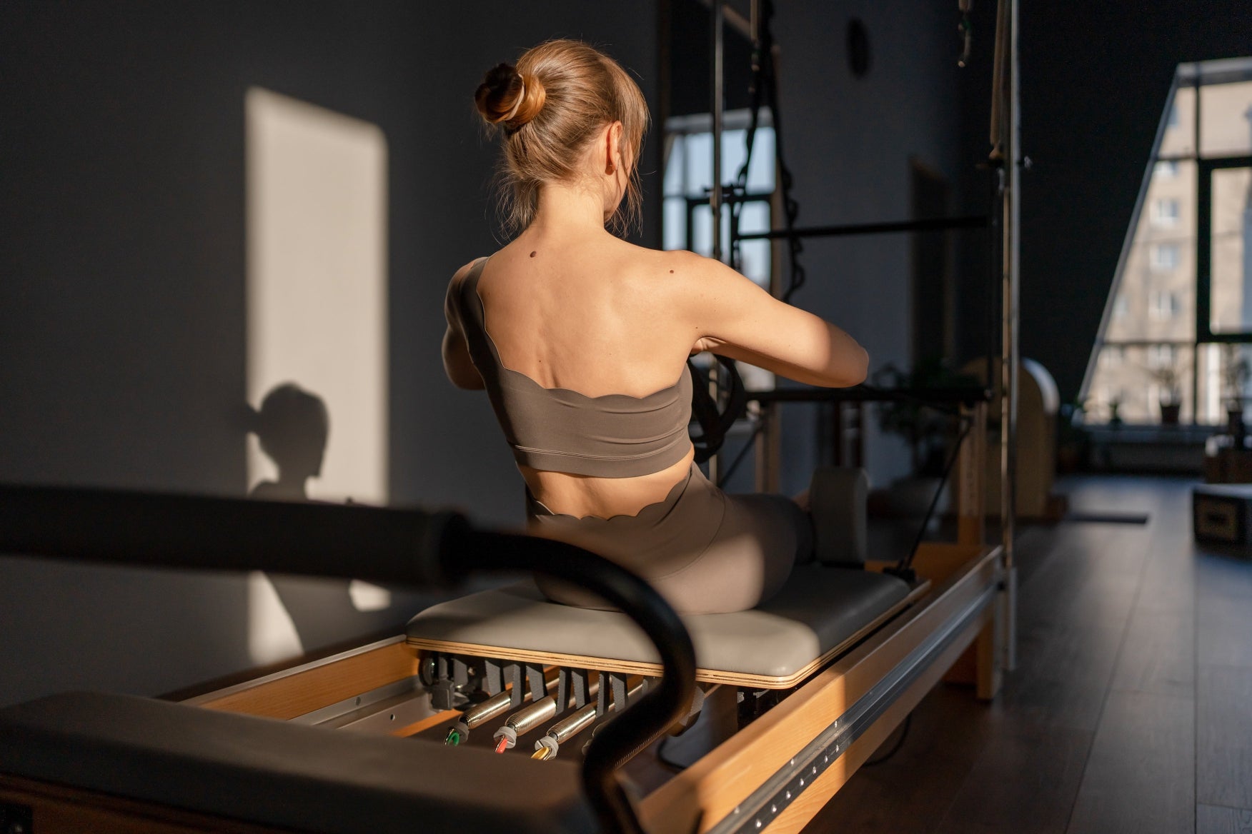 femme sur un reformer pilates avec tour de pilatesclubandco